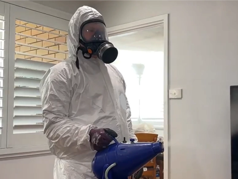 Technician in a protective suit and respirator working inside a home during mold removal in High Springs